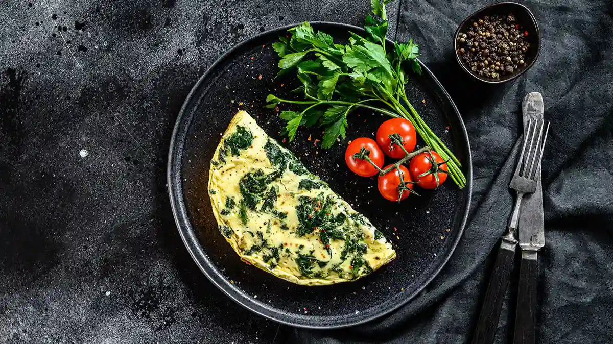 Omlet ze szpinakiem, natką pietruszki i pomidorkami to przykład śniadania na diecie na niedoczynność tarczycy, które nie wpływa negatywnie na wchłaniania lewotyroksyny.
